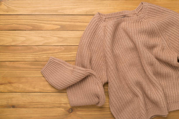 istock Brown sweater on wooden background, top view 2181214103