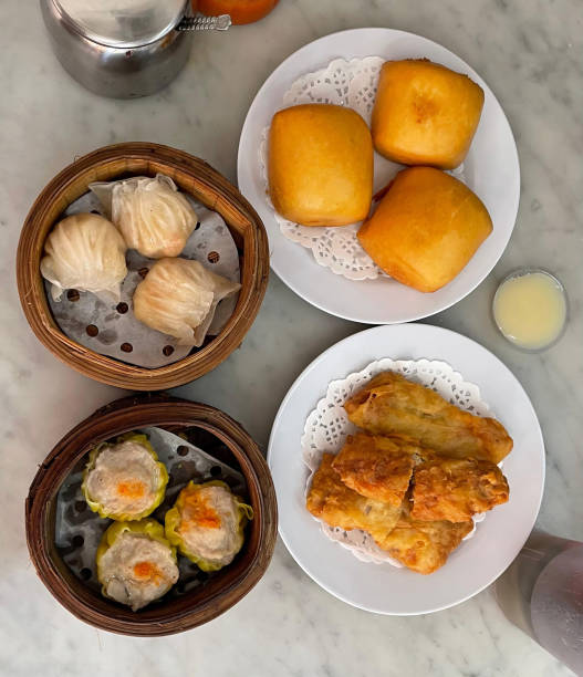 Top down view of four plates of freshly served dim sum on a marble table