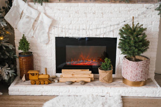 istock Fireplace with a train set and a potted christmas tree in front of it 2181220595