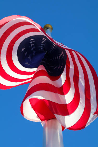 istock American flag blowing in the wind on the blue sky background 2181223163