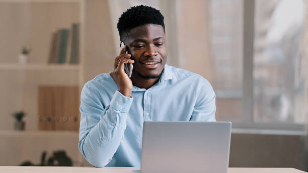 istock African american man businessman freelancer worker talk chatter on mobile cellphone with client make business call discussion listen news explain information looks at laptop screen use gadget service 2181227018