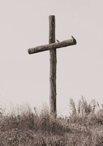 An old wooden cross against the sky in a field. Sepia