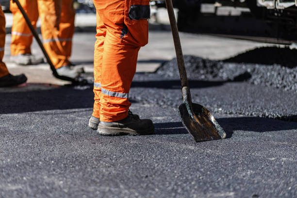 istock Construction workers paving a road with asphalt during a sunny day in a busy urban area, focusing on the shoveling process 2181233901