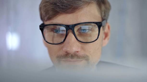 istock Businessman with glasses looking intently obscured partially by a translucent surface of laptop. Business concept 2181235064