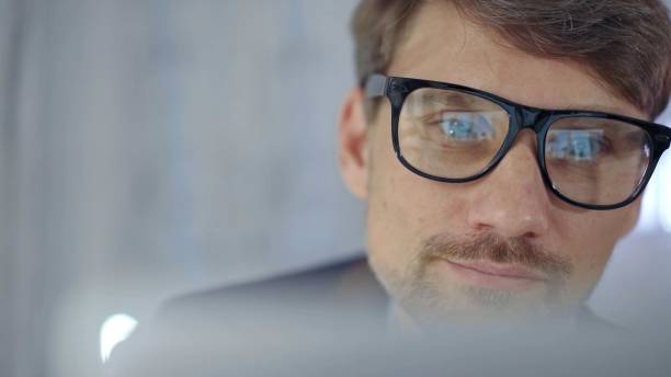 istock Businessman with glasses looking intently obscured partially by a translucent surface of laptop. Business concept 2181235935