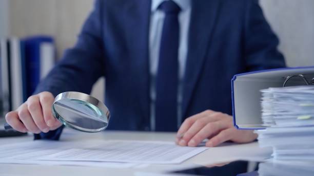 istock Businessman is carefully examining financial documents with a magnifying glass, highlighting the importance of thorough analysis in business. Audit and taxes 2181236330
