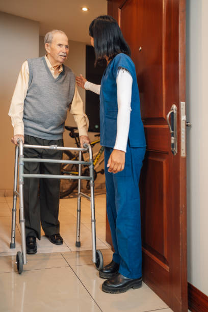 istock Old man with walker walking helped by a nurse 2181249882