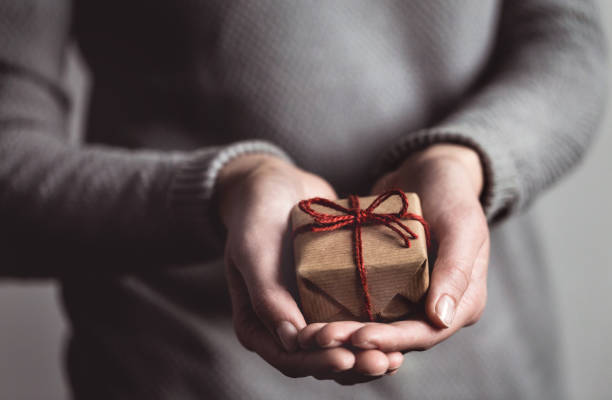 istock Hands holding little gift with red bow. Close up. 2181250194