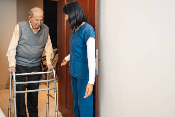 istock Old man walking with a walker next to a nurse 2181252533