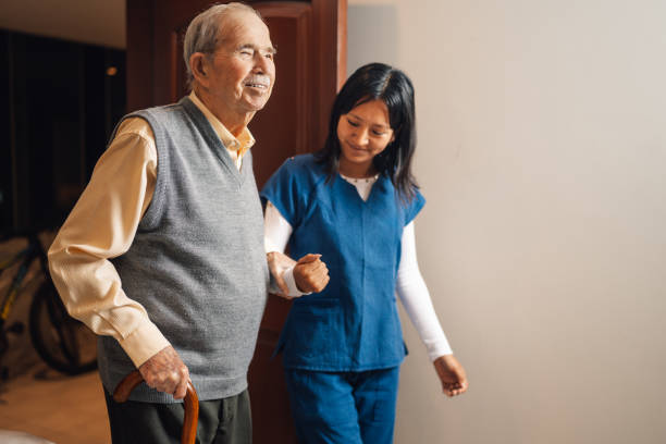 Nurse walking with an old man in a home visit