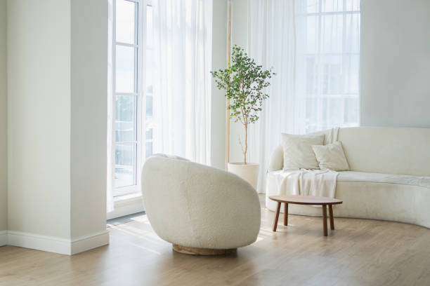 Stylish loft bedroom interior. Spacious design apartment with light walls large windows white couch sofa and armchair. Clean modern decoration with elegant furniture in minimalist Scandinavian style.