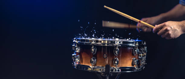 istock Drum sticks hitting snare drum with splashing water on black background. 2181265039