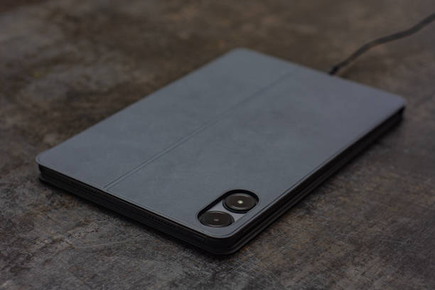 istock Digital tablet charges on the concrete table with a cable. Concept for charging the battery of gadgets. 2181266934