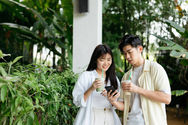 istock Young couple having fun talking, drinking coffee and using the phone while walking in the morning city 2181276782