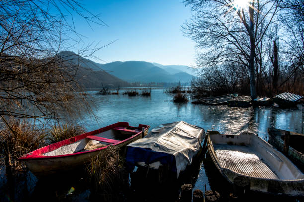 close up of parts of small fishing boats abandoned and covered with moss in the frozen waters of Lake Fimon in Vicenza