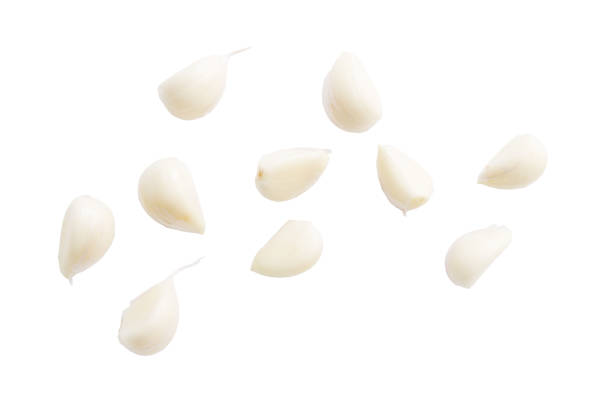 A close up of garlic cloves. The garlic cloves are sliced and scattered across the white background. Concept of freshness and naturalness, as the garlic cloves are a common ingredient in many dishes