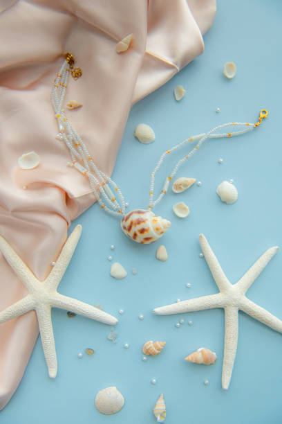 istock Pendant necklace made of a seashell and white beads surrounded by small seashells, starfish, pearls 2181285458