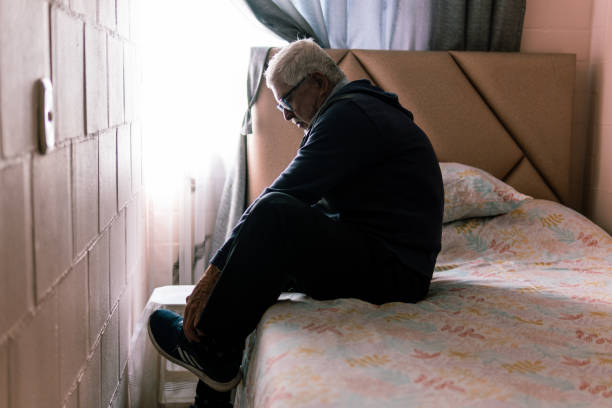istock Elderly man sitting on a bed, tying his shoes 2181287427