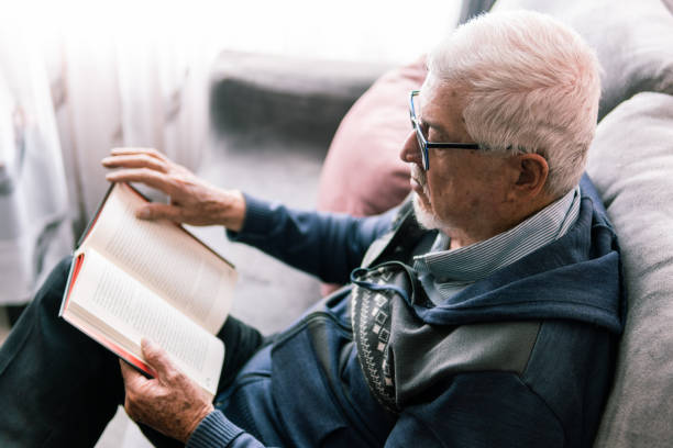 istock Senior man reading a book on the couch 2181287758