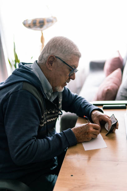 istock Elderly man jotting down notes at his desk 2181287853