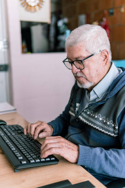 istock Elderly man typing on a keyboard at home 2181288281