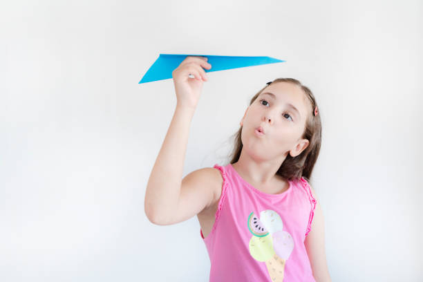 Little girl with paper plane on white background