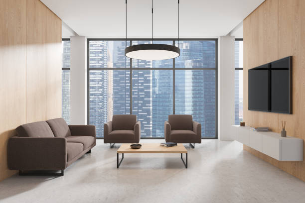 istock A modern office lounge area featuring comfortable brown sofas, a wooden coffee table, and a large TV on wooden walls. The background shows a cityscape through large windows. 3D Rendering 2181290834