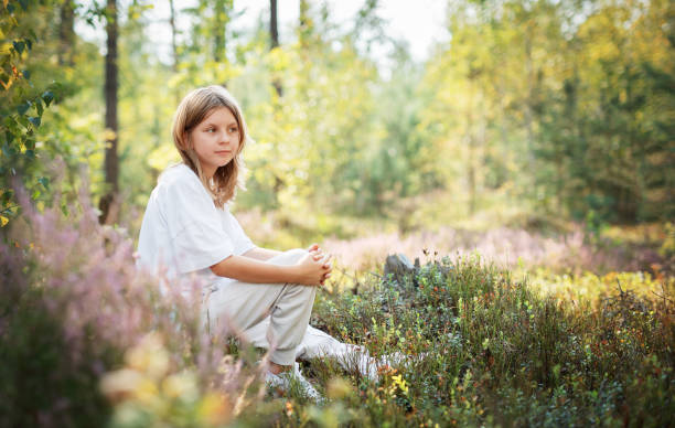 istock A young child sits peacefully among wildflowers in a serene forest during a bright summer afternoon 2181291206