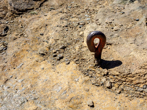 Empty old iron hook anchor into sandstone rock in trekking patch with copy space, summer sport activity tools for climbing at the stone mountains.