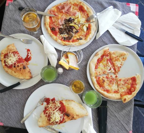 A table in a restaurant on which there are plates with slices of pizza, cutlery and glasses with juice and beer
