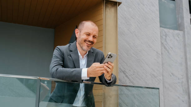 A businessman types a message on his phone on a modern office terrace. A comfortable spot for work and connecting with partners.