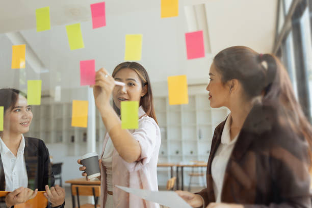 istock Asian businesswoman teamwork planning with sticky notes and new ideas on a glass wall. 2181308607