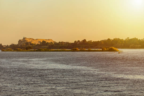 A small village with mud huts and a mosque with a minaret on the banks of the Nile. In the foreground, a fishing felucca. Please not taht the image were scanned from an old negative.