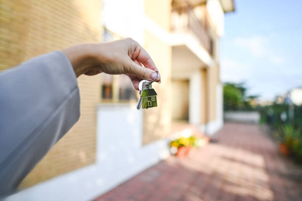 Midsection Of Businessman Holding Model House Against Wall