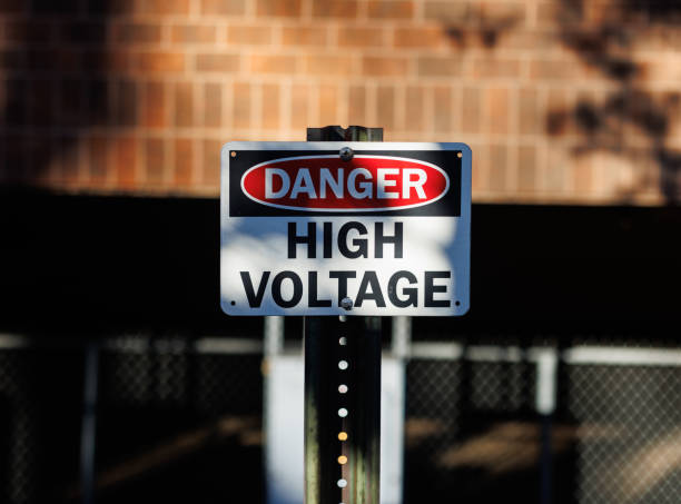 Close-up of a rectangular metal Danger High Voltage sign on a metal pole. Selective focus.