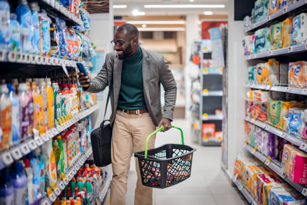 istock Smiling Man Shopping in a Supermarket While Using Smartphone 2181313066