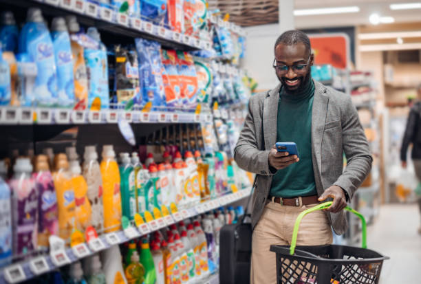 istock Man Shopping in Supermarket Aisle While Using Smartphone 2181313083