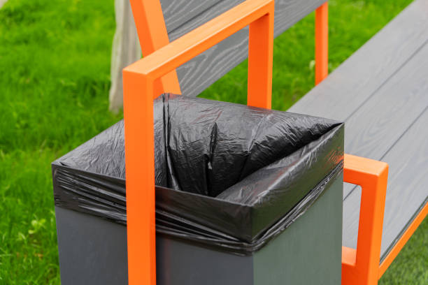 istock This container, featuring a black bag, is designed for waste disposal and recycling. It is conveniently situated beside a colorful park bench in a lush green space 2181315378
