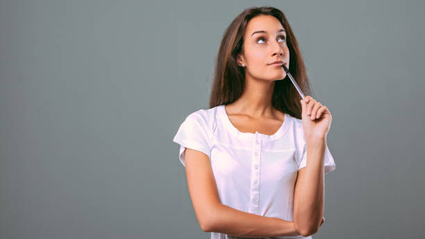 istock Pensive young woman brainstorming creative ideas on gray backgro 2181316094