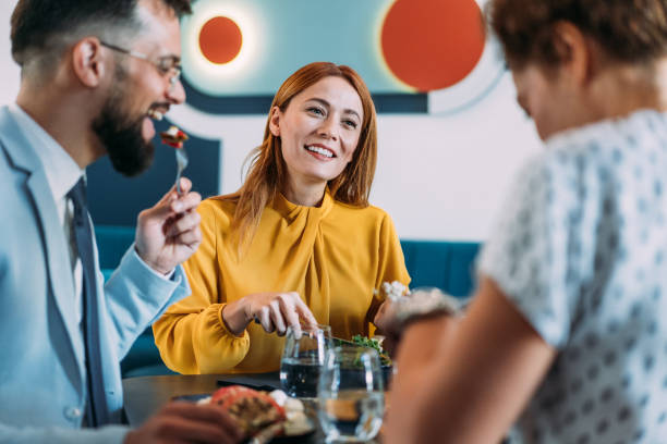 Happy business colleagues talking while eating lunch in a restaurant.