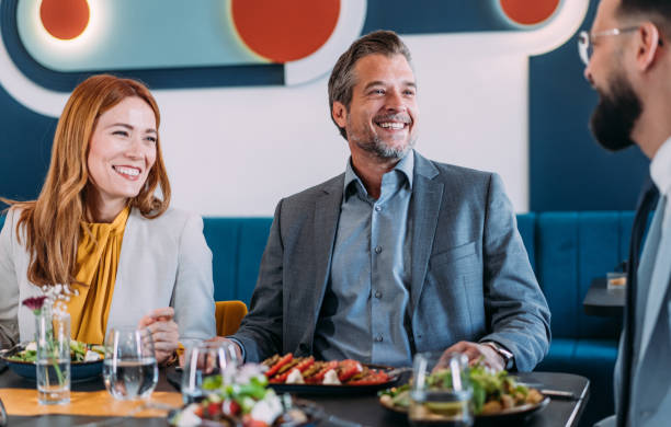 istock Happy business colleagues talking while eating lunch in a restaurant. 2181317880