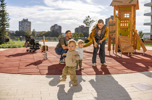 istock Twin baby boys making their first steps on playground with their parents 2181318007