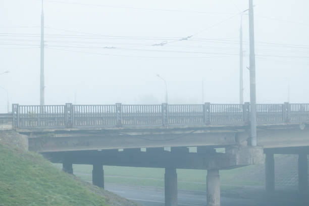 ugly poor Eastern Europe city scape element concrete bridge frame work pattern above car road with pillars in mist smoky weather polluted landmark urban environment