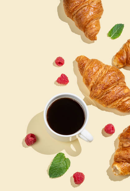 istock Flat lay of espresso coffee cup, fresh croissants, raspberry and mint leaf  on yellow background with shadow. 2181322224