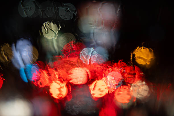 A blurry image of a car with red lights and a blurry background. The image has a moody and dreamy feel to it, as if it were a painting or a photograph. The colors are vibrant