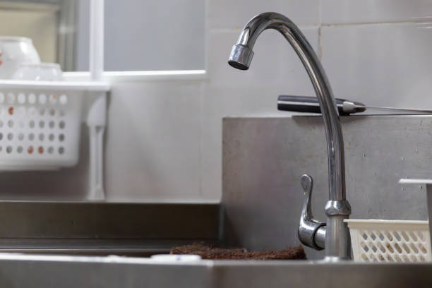 A sink with a silver faucet and a brown towel on it. The sink is dirty and the towel is wet