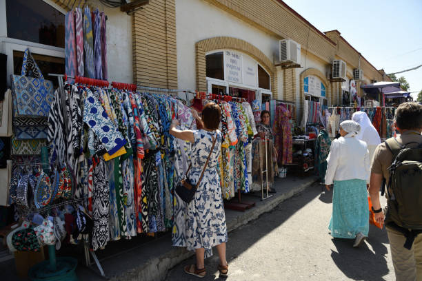 Samarkand, Uzbekistan - September 10, 2024: female tourist examines goods on street market nearby Siab bazaar local fruit vegetable and spices market