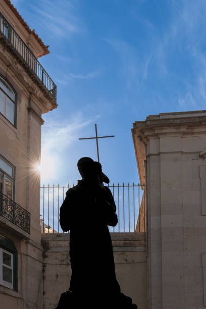 Moment of grace. Early morning sunlight embraces a sculpture with a Christian cross. Back lit. Silhouette.