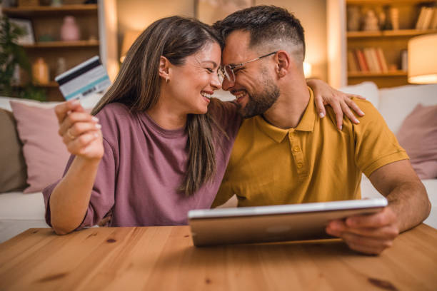istock A loving couple embraces each other while shopping online using a credit card and a digital tablet 2181366523