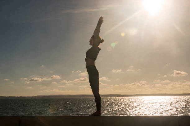 istock silhoutte of a woman practicing yoga standing mountain pose. 2181366573
